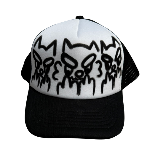 A black and white trucker hat featuring three stylized black skull graphics on the white front panel, with a black mesh back and black brim.